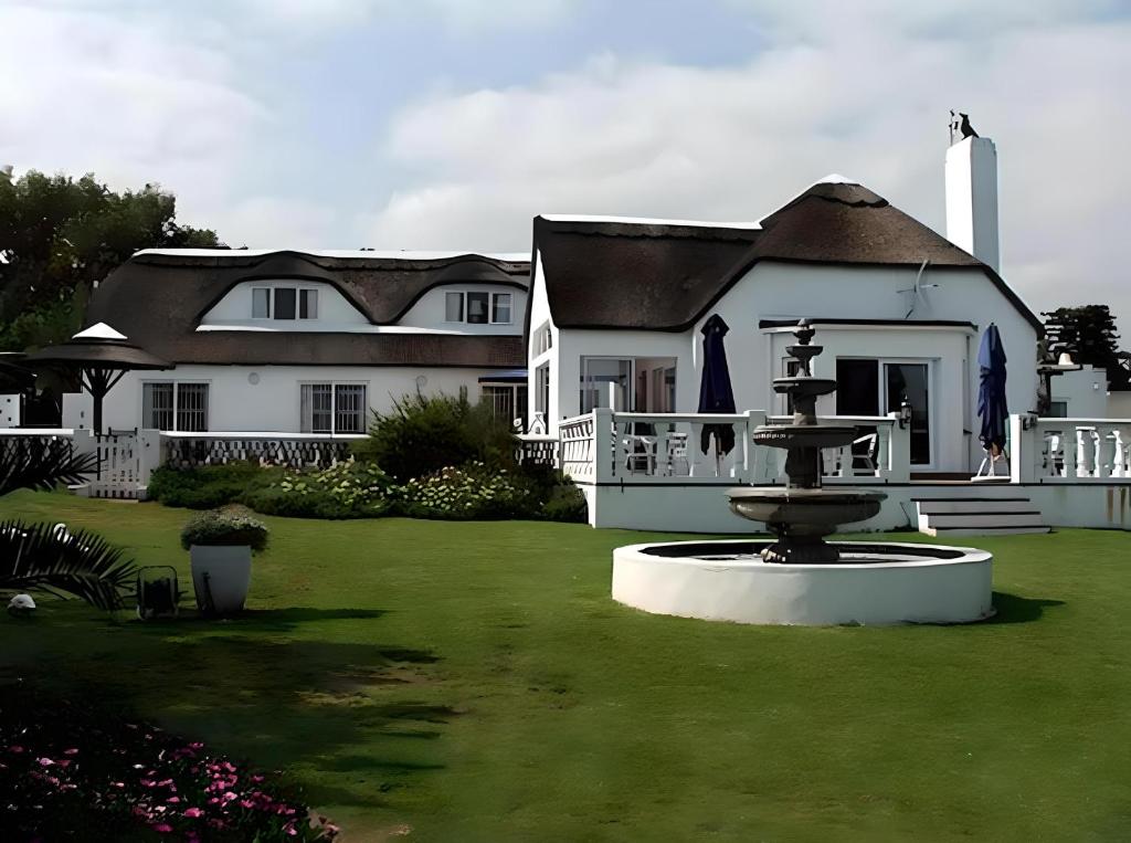 a large white house with a fountain in the yard at Lagoon Lodge in Cape Town