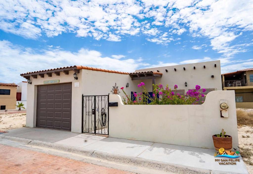 een wit huis met een garage en bloemen aan de zijkant bij La Hacienda San Felipe Dream Home - Casa Sonora in San Felipe