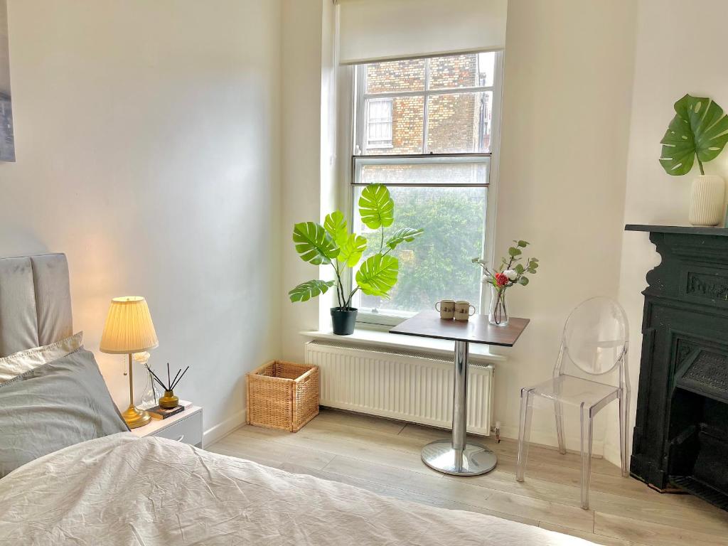 a bedroom with a bed and a window with plants at Spacious 2 Bedrooms Flat Archway Station in London