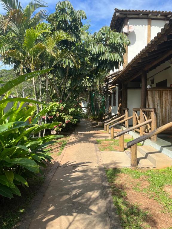 einen Weg neben einem Haus mit Bäumen und einem Zaun in der Unterkunft Pousada Vila Cambury in Camburi