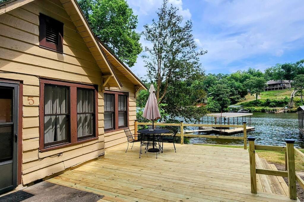 une terrasse en bois avec une table et un parasol dans l'établissement #05 - Lakefront Two Bedroom Cottage- Pet Friendly, à Hot Springs