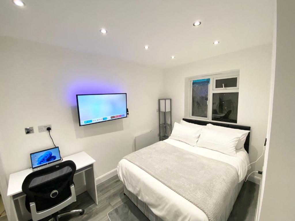 Schlafzimmer mit einem Bett, einem Schreibtisch und einem TV in der Unterkunft London Studio in Chingford