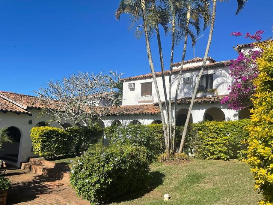 ein weißes Haus mit Palmen und einem Garten in der Unterkunft Casa em condomínio a 50mt da praia dos ossos in Búzios