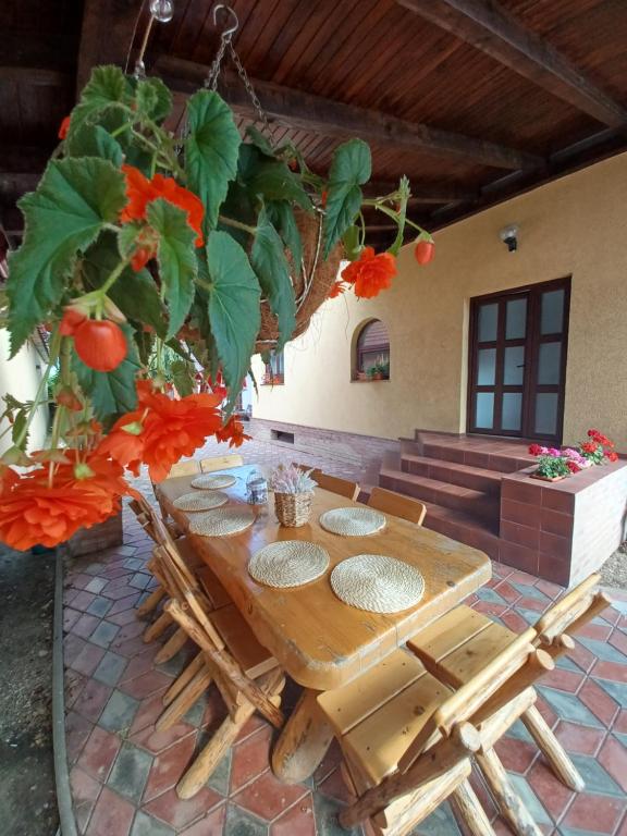 a wooden table and chairs in a patio with flowers at Vila Gloria ,Brașov in Ghimbav