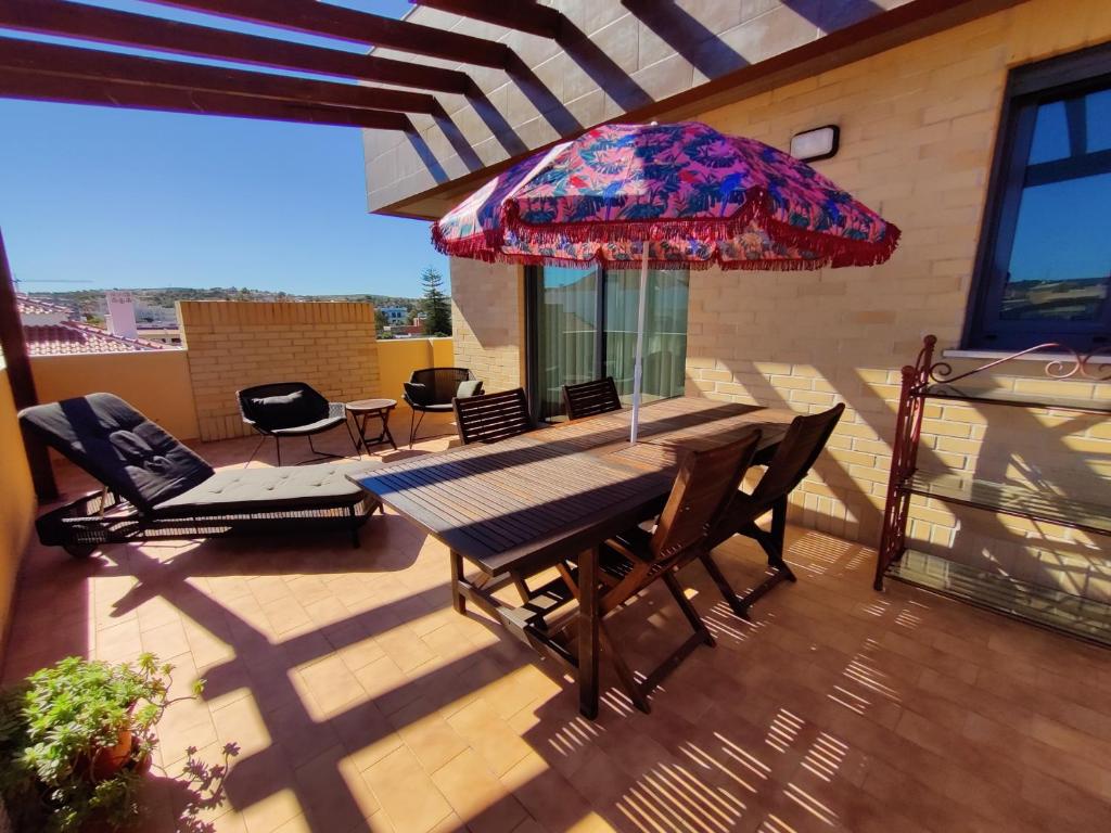 Algarve 360º Experience في Campina de Cima: فناء مع طاولة وكراسي ومظلة