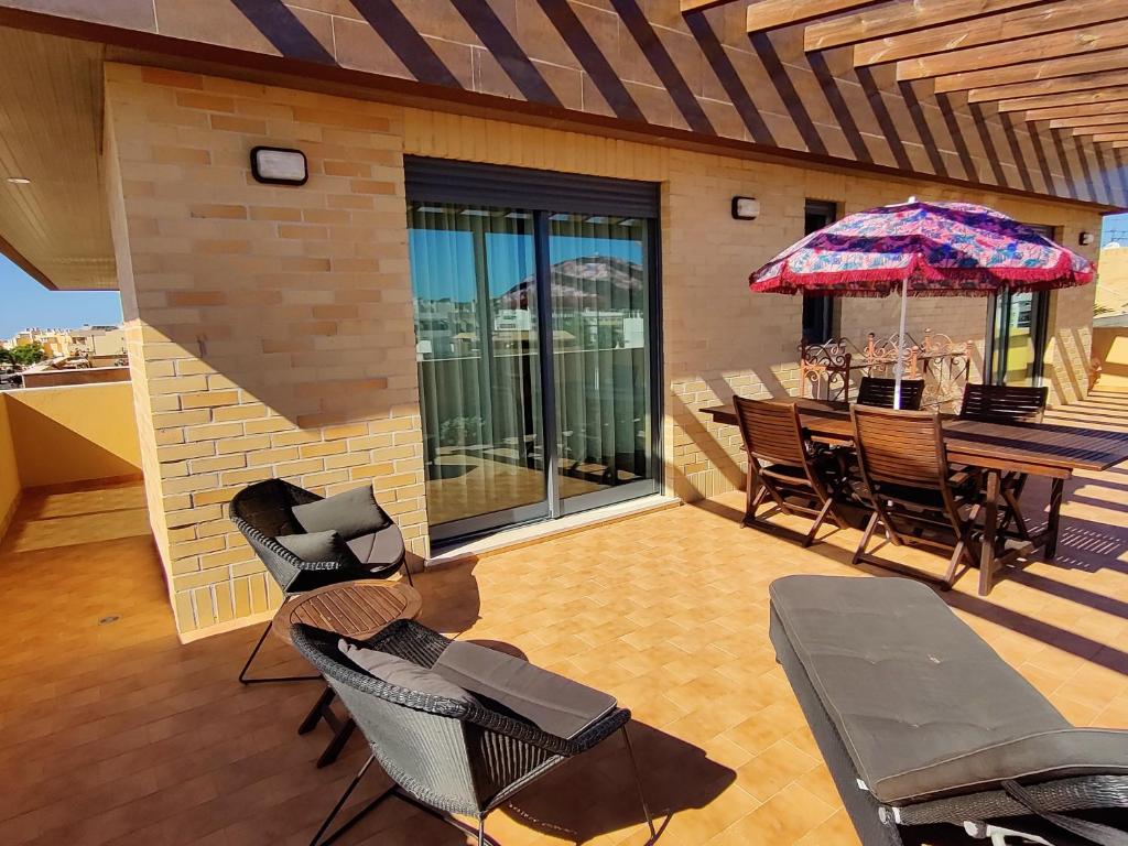 a patio with a table and chairs and an umbrella at Algarve 360º Experience in Loulé