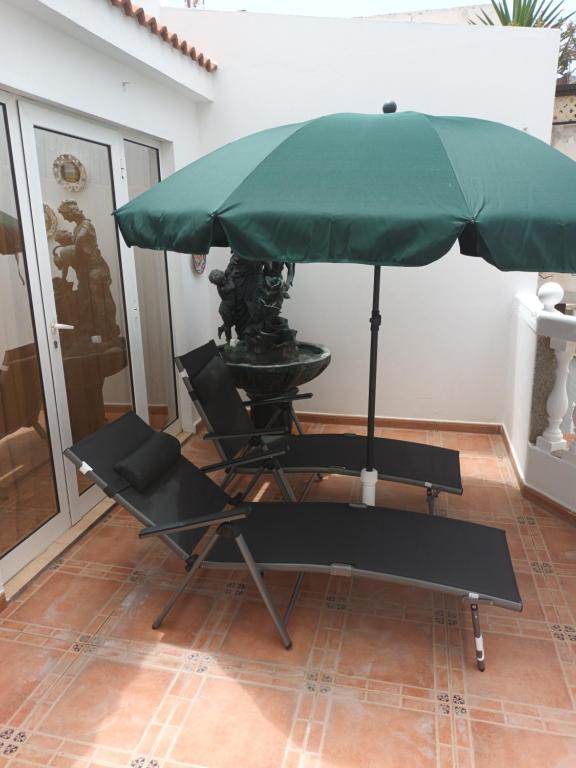 a green umbrella and two chairs under a table at Apartamentos As de guía, playa de las canteras in Las Palmas de Gran Canaria
