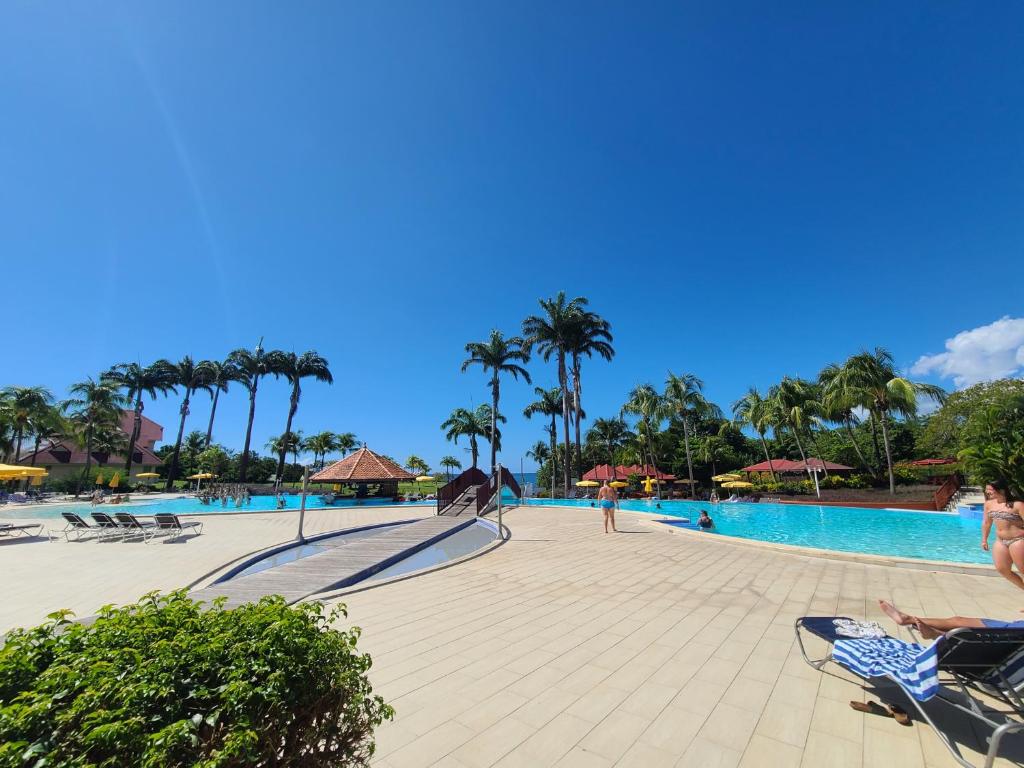 a pool at a resort with palm trees at Studio village vacances sainte luce C6 in Sainte-Luce