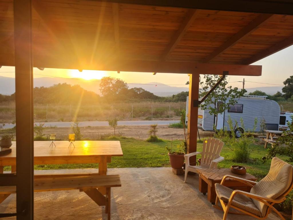 einen Tisch und Stühle auf einer Terrasse mit Blick auf den Sonnenuntergang in der Unterkunft פינה קסומה בגליל in Kibbuz Dafna