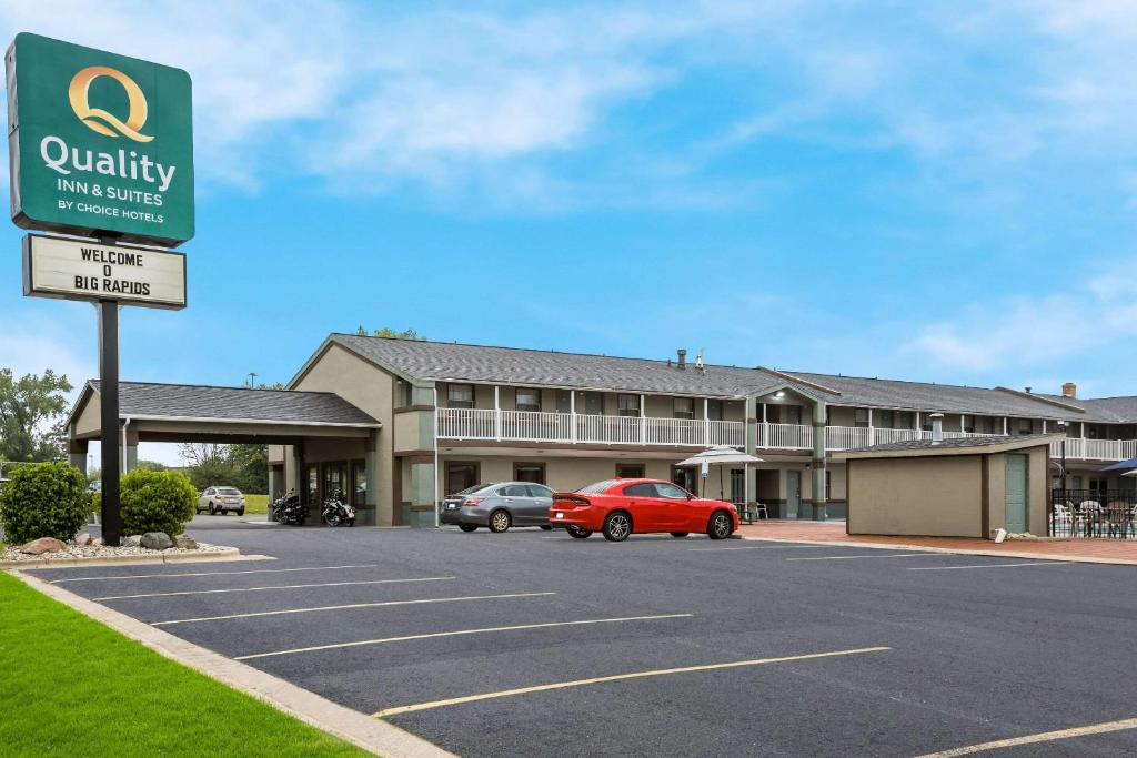 ein Gebäude mit einem roten Auto auf einem Parkplatz in der Unterkunft Quality Inn & Suites in Big Rapids