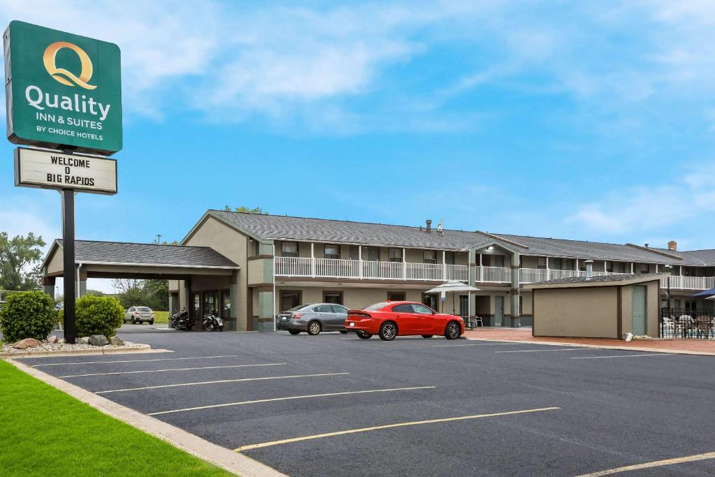 a building with a red car parked in a parking lot at Quality Inn & Suites Big Rapids near University in Big Rapids
