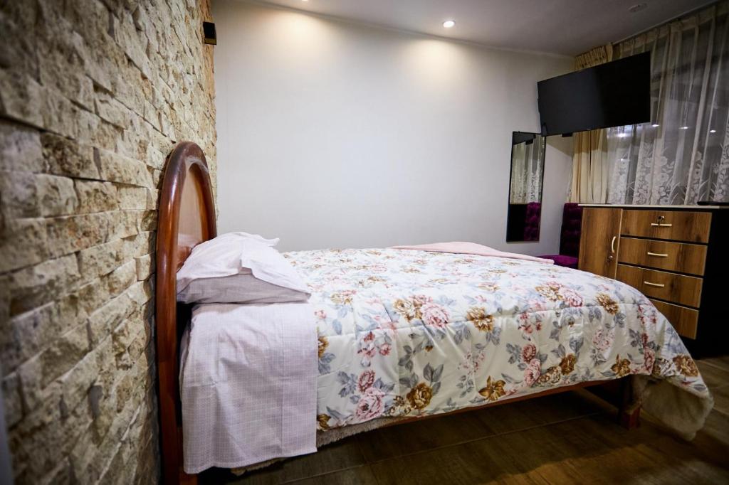 a bedroom with a bed and a brick wall at Casa de Juli in Huancayo