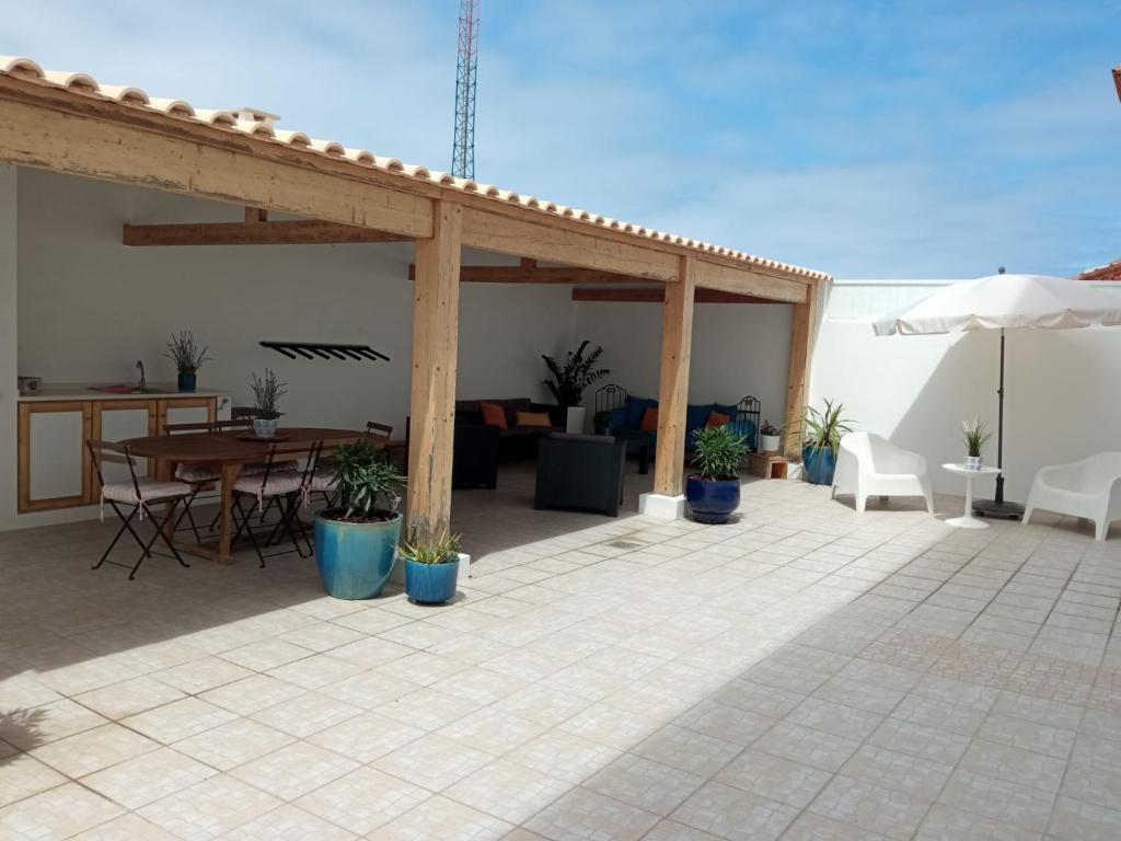 a patio with a table and chairs and an umbrella at White Guest House in Peniche