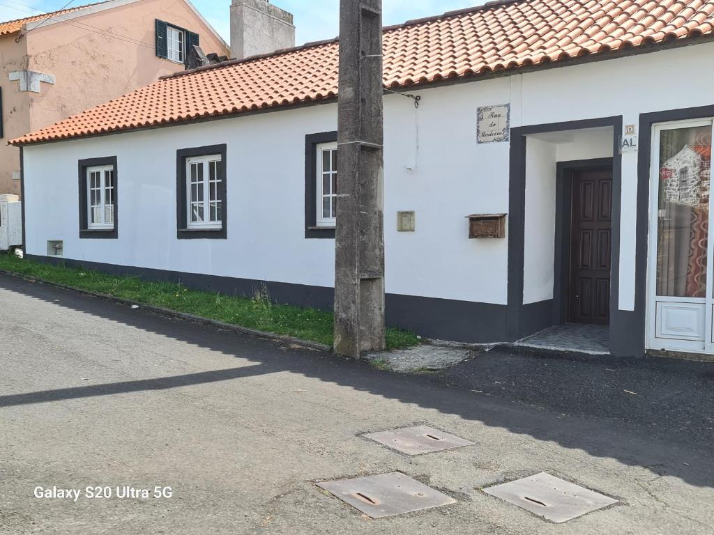 a white building with a door on a street at AP Luso Brasileiro in Lajes das Flores