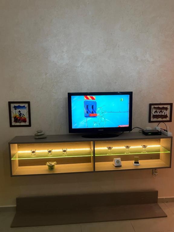 Bel appartement a tanger beach في طنجة: جلسة تلفزيون فوق رف خشبي