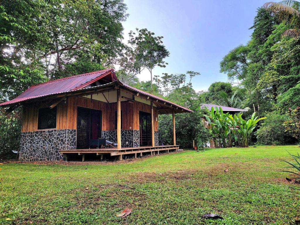 un piccolo edificio con portico in un campo di Corcovado Guest House a Bahía Drake