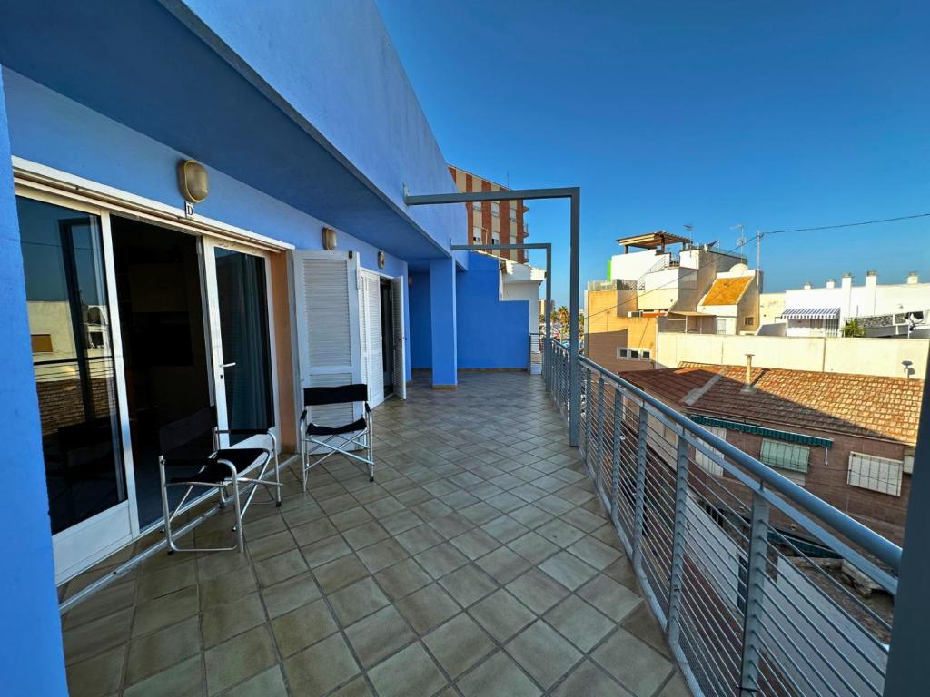 - un balcon avec 2 chaises et un bâtiment bleu dans l'établissement Loft a Pasos del Puerto y Playa en Lo Pagán, à Lo Pagán