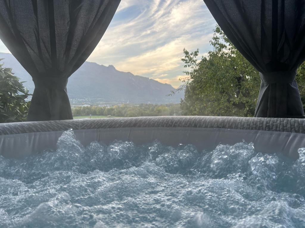 uma banheira de hidromassagem com vista para uma montanha em The Tiny home avec jacuzzi 5 min du lac du Bourget 10 min d Aix les bains et Chambery em Voglans