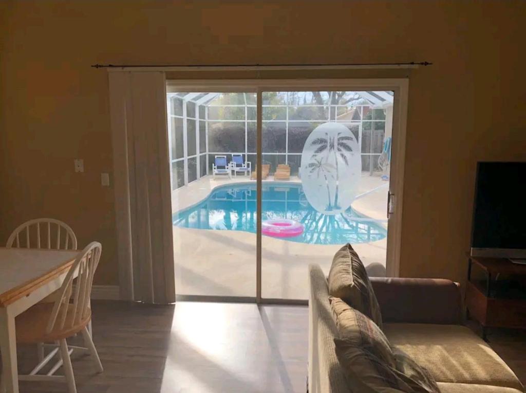 uma sala de estar com uma porta de vidro deslizante para uma piscina em Guest house withl kitchen living room 65" tv solar heated pool em Palm Coast
