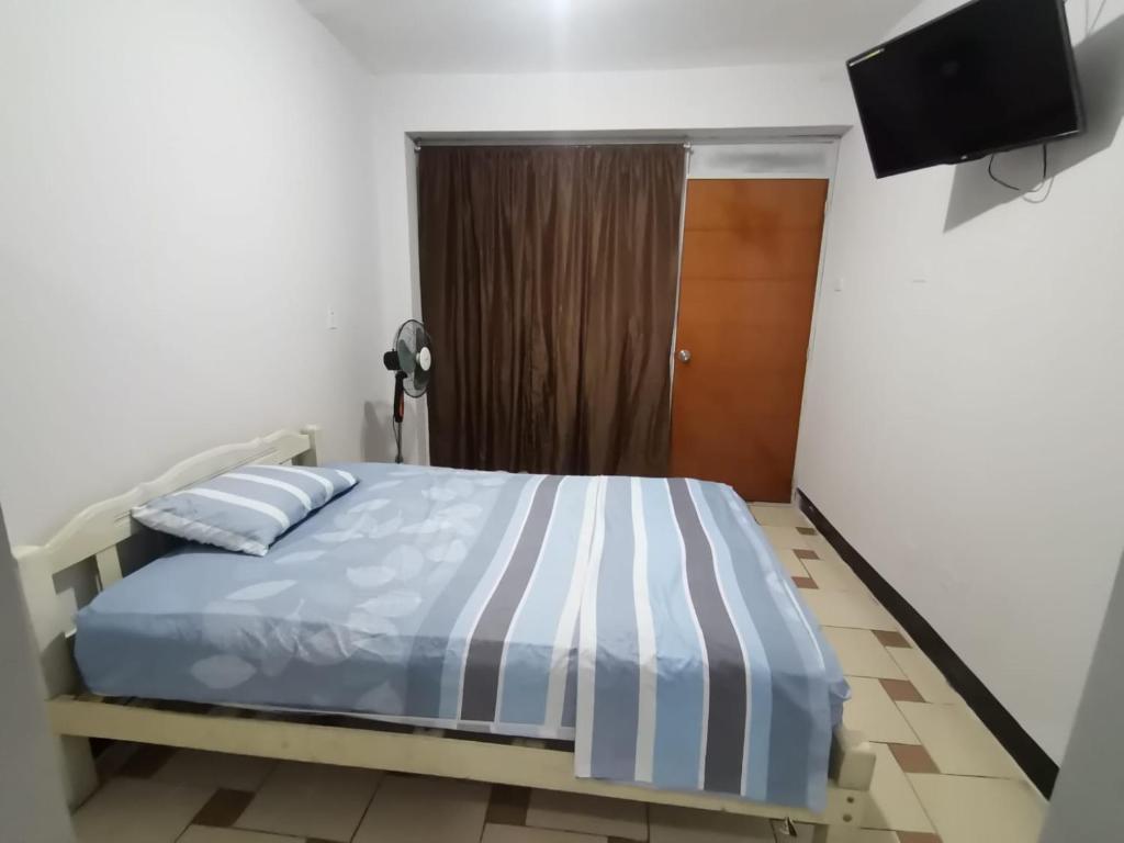 1 dormitorio con 1 cama y TV en la pared en Hotel JK en Pucallpa