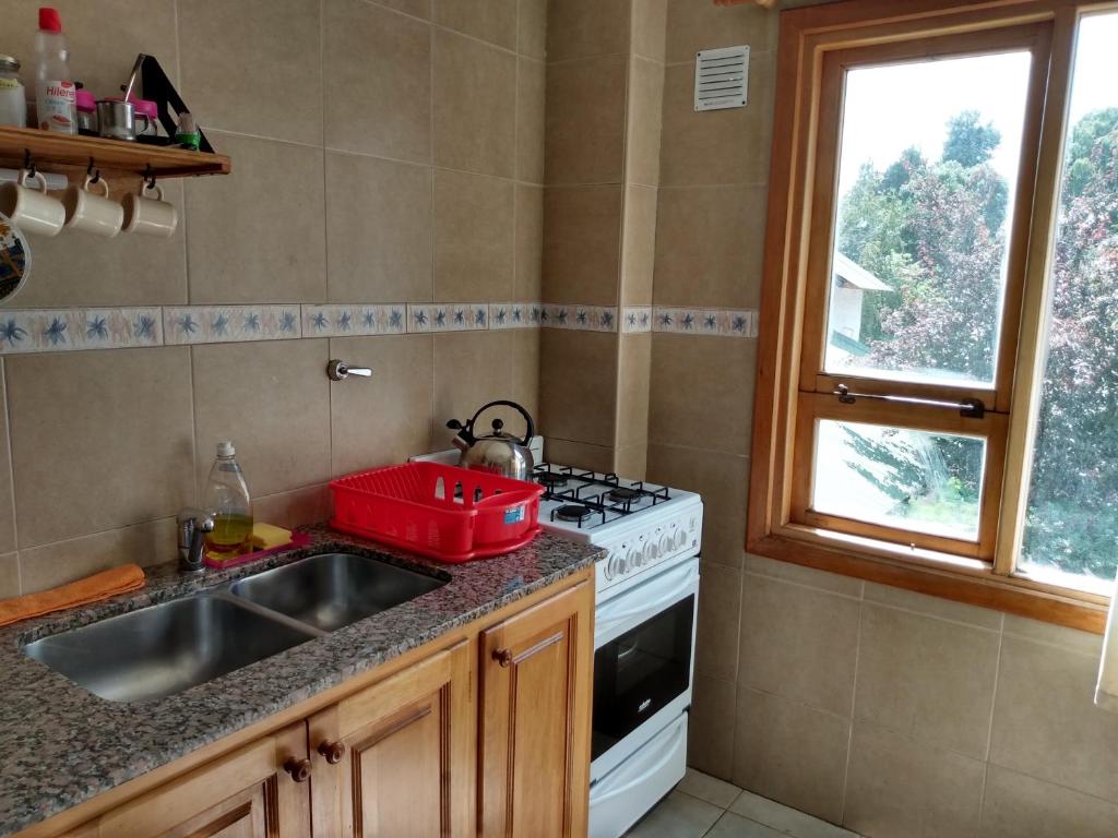 eine Küche mit einer Spüle, einem Herd und einem Fenster in der Unterkunft Virgen de las Nieves in San Martín de los Andes