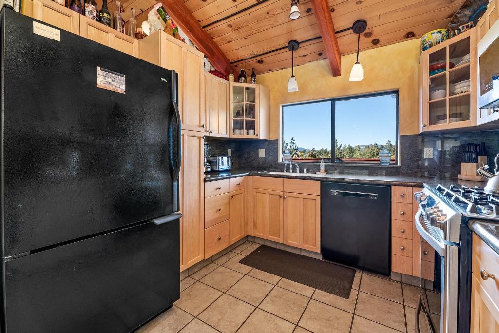 een keuken met een zwarte koelkast en een raam bij King's Cabin - Spacious mountain home with picturesque views, fast internet! in Big Bear Lake