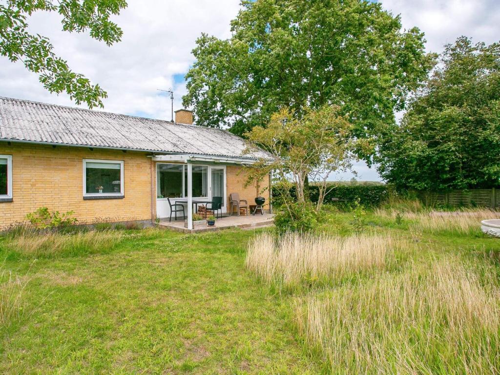 una pequeña casa amarilla con patio en 6 person holiday home in Tranek r, en Tranekær