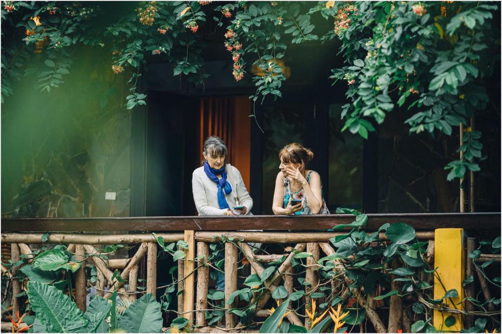 two women sitting on a fence looking at their cell phones at Trang An Ecolodge in Ninh Binh
