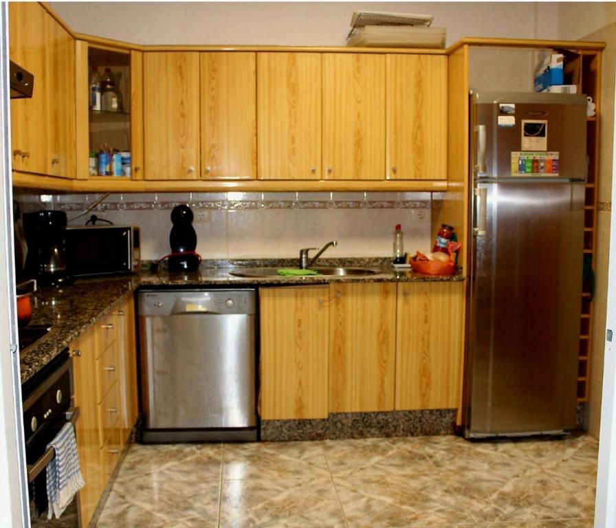 eine Küche mit Holzschränken und einem Kühlschrank aus Edelstahl in der Unterkunft Terrazas del Sur in Los Abrigos