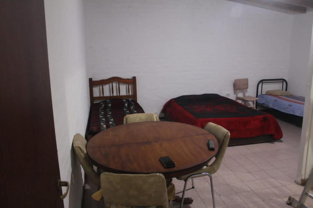 a room with a table and a bed and a table and chairs at Casa Huarpes in Mendoza