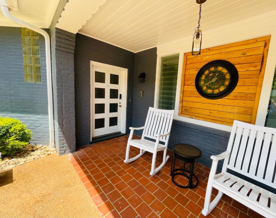 a porch with two white chairs and a clock on it at Sonsak - Unit 1 in Charlottesville