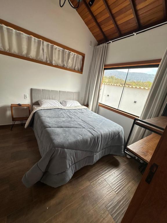 1 dormitorio con cama y ventana grande en chalé cantin casa temporada 900 m praça tiradentes, en Tiradentes