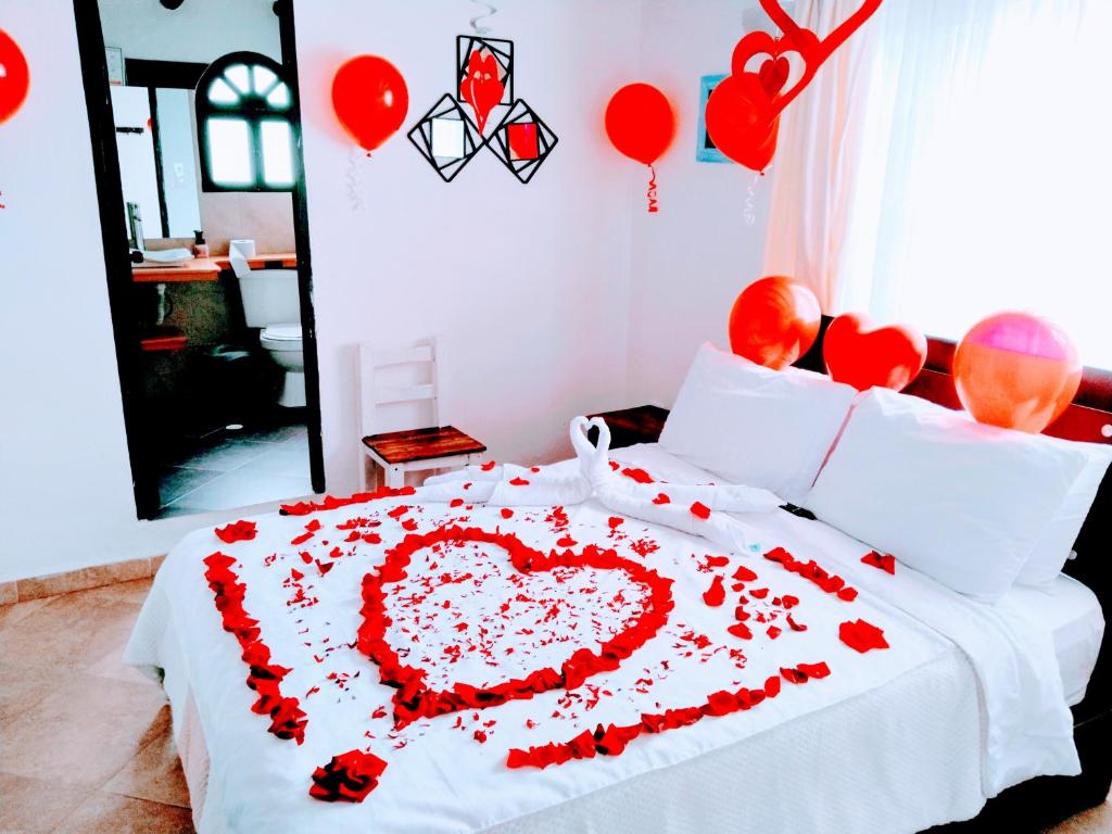 Una cama con un corazón hecho de flores rojas en casa Hotel la Tranquera, en Villa de Leyva
