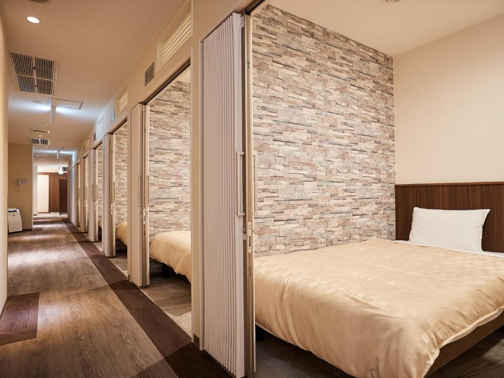 a room with two beds and a brick wall at Grand Cabin Hotel Naha Oroku for Women / Vacation STAY 62324 in Naha