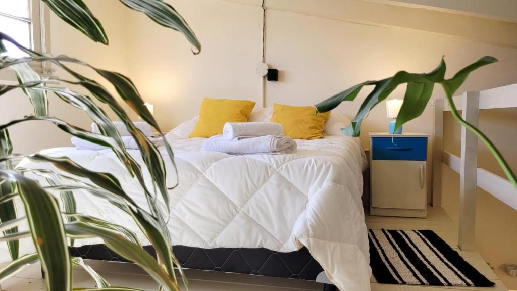 a bedroom with a bed with yellow pillows and a plant at Interra Apart 1 Temporario in Salta