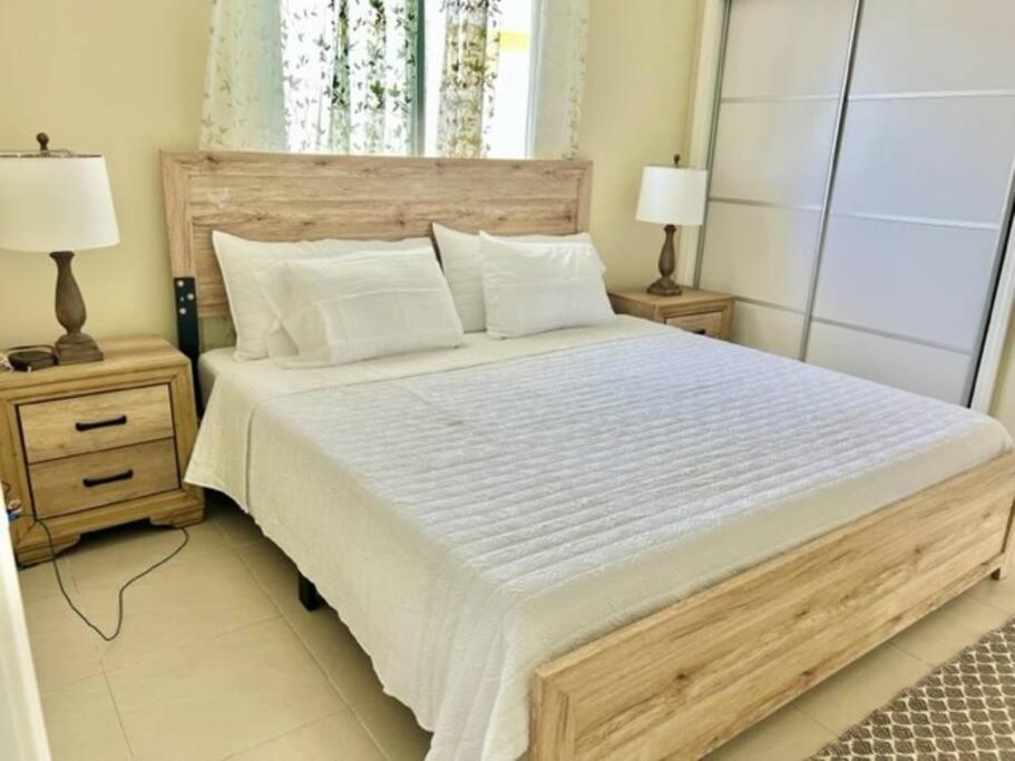 a bedroom with a large white bed with two night stands at FlowerPot by the Sea in Lucea