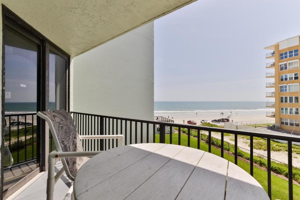 a table and chair on a balcony with a view of the beach at 1 Bedroom -1 Bath With Ocean Views At Ocean Trillium 302 in New Smyrna Beach