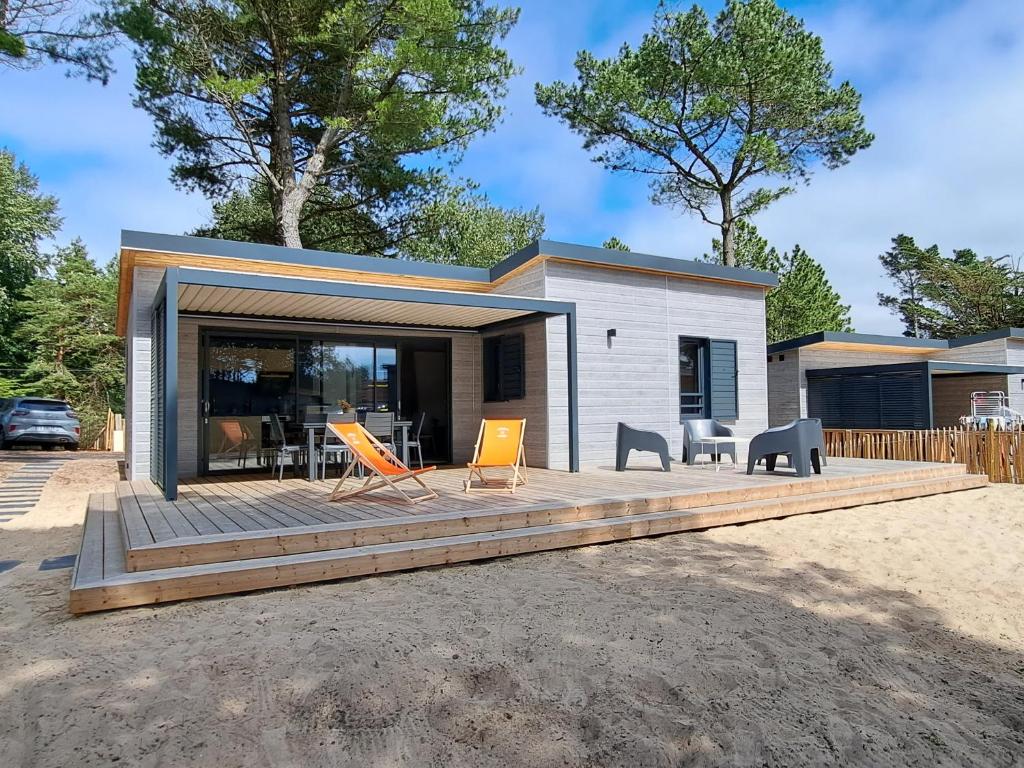ein Haus mit einer Terrasse und Stühlen davor in der Unterkunft Chalet standing, 6 couchages, piscine chauffée, terrasse privée, proche plage et commerces - FR-1-361-520 in Jullouville-les-Pins