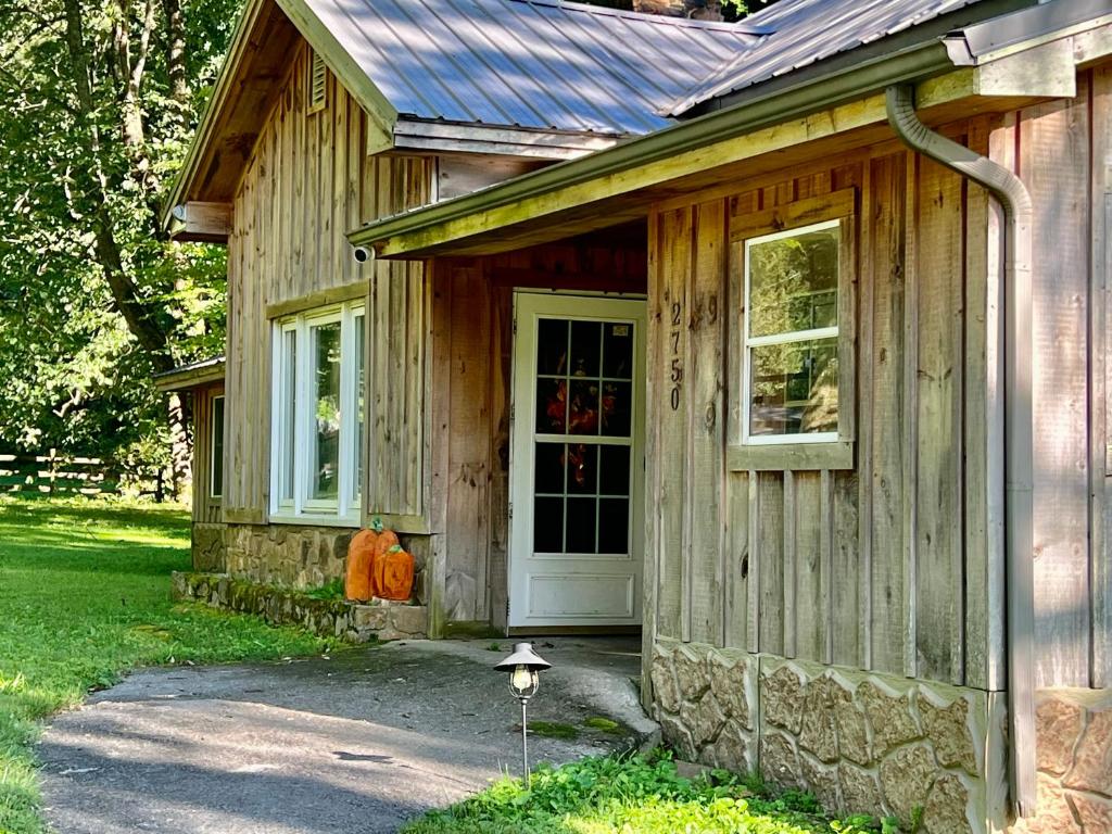 une maison en bois avec une porte et une citrouille devant dans l'établissement The Hillbilly Hideaway with Hot Tub, Creek, & Outdoor Games, à Sevierville