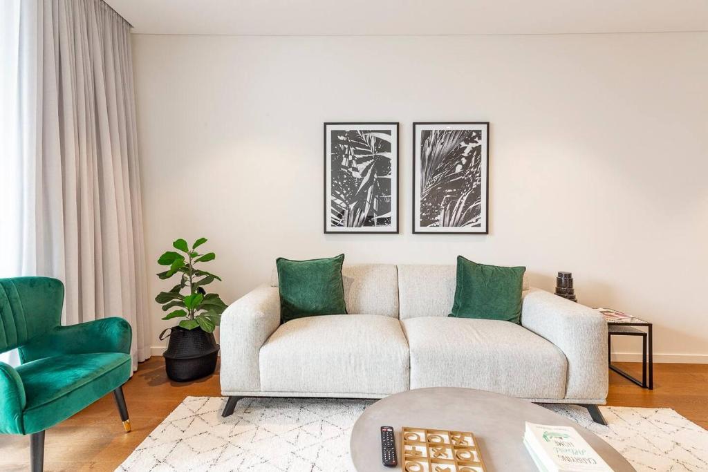 a living room with a white couch and green chairs at Sunny Courtyard Escape in Sydney's Little Italy in Sydney