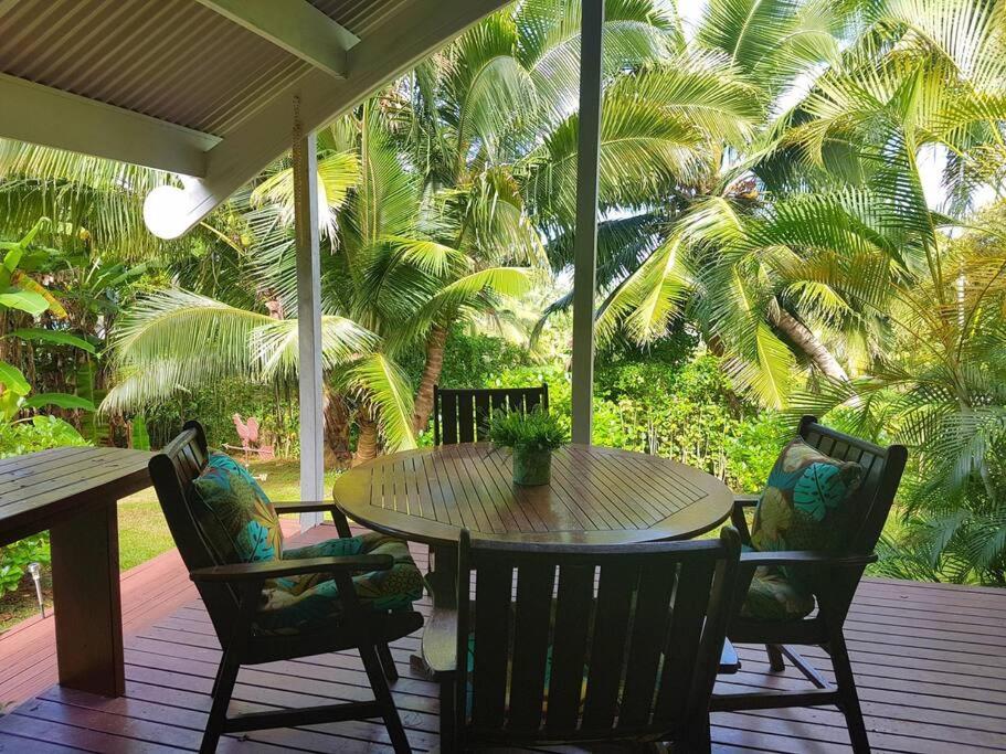 een tafel en stoelen op een veranda met palmbomen bij Are Ara - House of Pineapple in Titikaweka