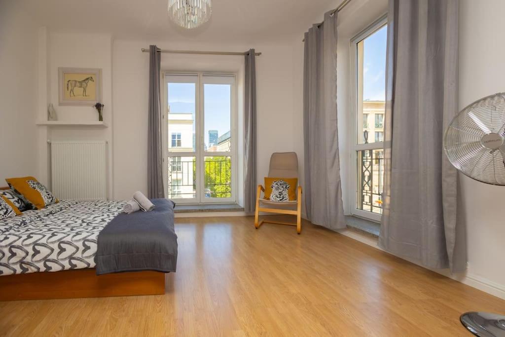 een slaapkamer met een bed en 2 grote ramen bij Spacious Apt in heart of Warsaw in Warschau