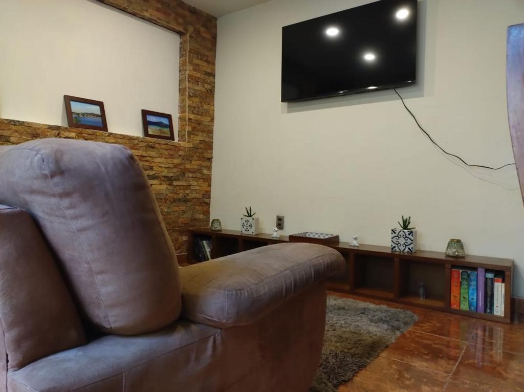 a brown leather chair in a living room with a flat screen tv at Casa del primo in Ixtapaluca