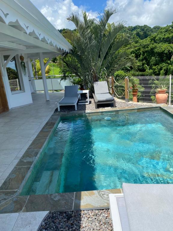 a swimming pool with two chairs and a table at Les Appart villa Sunbay Caraibes avec piscine privative vue mer et montagne in Le François
