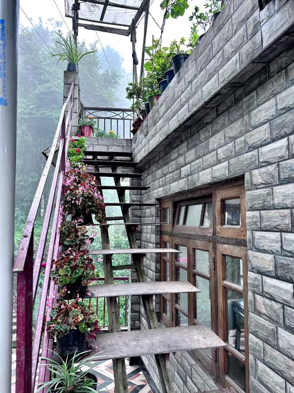 a stone building with a wooden staircase next to a door at Syengden Nikunj in Darjeeling