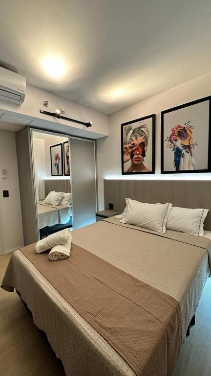 1 dormitorio con 1 cama grande y espejo en Blend Marista, en Goiânia