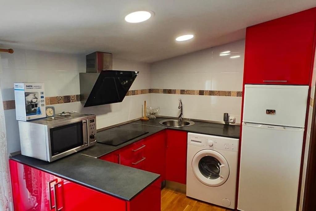 uma cozinha com armários vermelhos e uma máquina de lavar roupa em Apartamento cerca de la playa em Santander