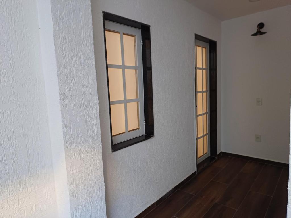 um quarto vazio com duas janelas e um piso de madeira em Loft em Olaria no Rio de Janeiro