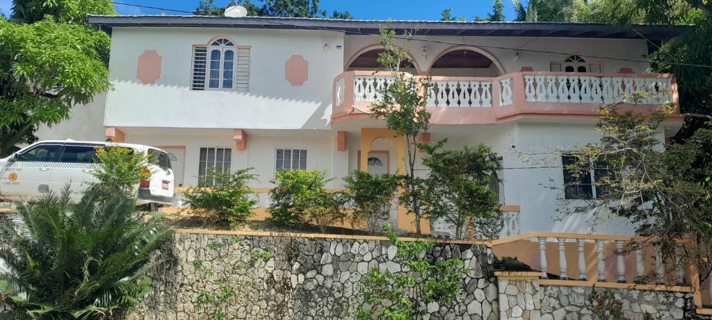 une maison blanche avec une voiture blanche garée devant elle dans l'établissement Cozy Family Inn, à Port Antonio