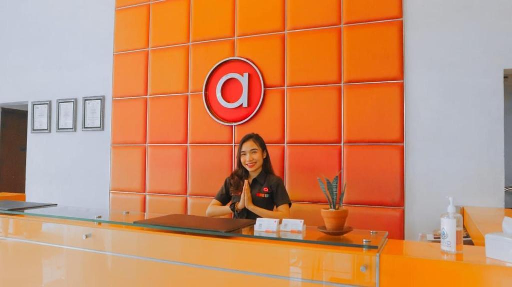 a woman standing behind a counter in an orange wall at Amaris Hotel Cihampelas in Bandung